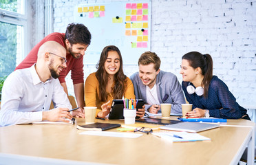 Young startup businesspeople looking tablet during brainstorming meeting. Group of university...