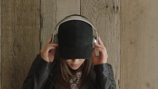 close up portrait of trendy young hispanic woman student enjoying listening to music wearing headphones confident stylish female looking serious at camera