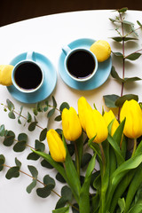 Fototapeta na wymiar two blue cup of coffee with yellow tulips on an old table, top view