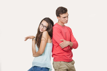 Studio shot of disgruntled couple wearing casual clothes standing back to back frowning their...