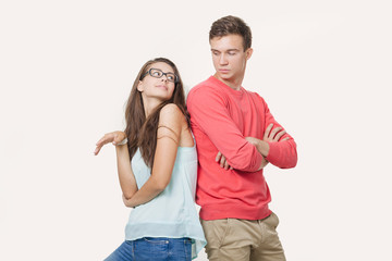 Studio shot of disgruntled couple wearing casual clothes standing back to back frowning their...