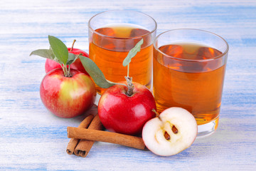 Apple juice with fresh ripe apples and cinnamon sticks on a blue wooden background