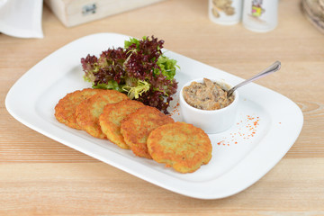 Traditional Belarus potato pancakes (draniki) with sauce cream in a plate at a cafe