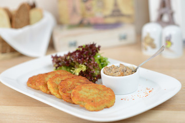 Traditional Belarus potato pancakes (draniki) with sauce cream in a plate at a cafe