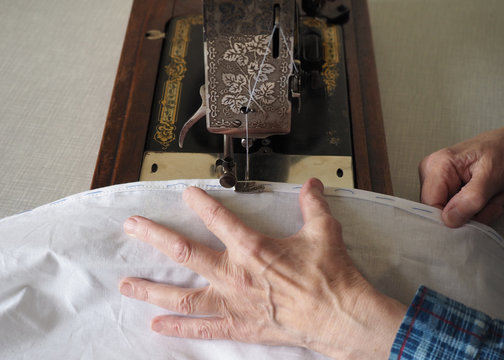 Sewing process. Foot of old vintage sewing machine and hand. Selective focus