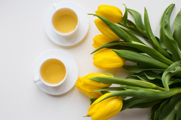 Fototapeta na wymiar beautiful yellow tulips, two cups of green tea, spring