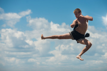 Fototapeta premium Man flying kick in sky background
