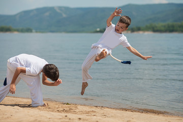 Training of two children on the beach: capoeira, sports