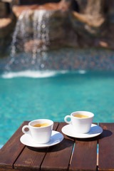 Fototapeta na wymiar Two cups of coffee on the table near the pool.