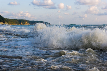 sea landscape is a pebbly beach with waves in white foam