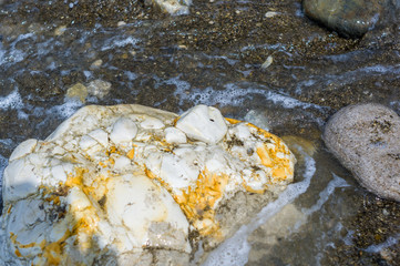 pebble stones on the sea beach, the rolling waves of the sea with foam