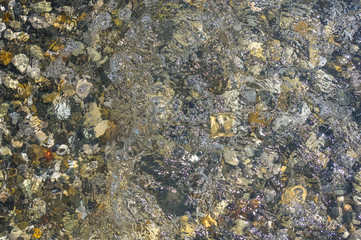 sea pebble beach with multicoloured stones, waves with foam