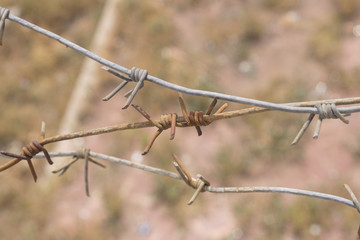 rusty barbed wire on blurred brown background
