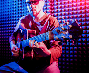 Obraz premium Young man playing on the acoustic guitar in sound recording studio.