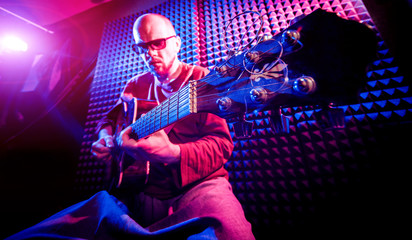 Young man playing on the acoustic guitar in sound recording studio.