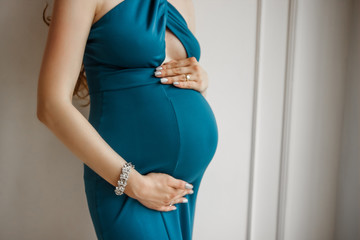 Pregnant woman on the ninth month in a blue dress.