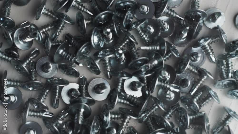 Aufkleber Macro screws rotating on a metal table and black background. Seamless loop.