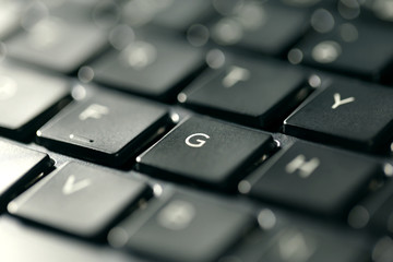 Macro view of black laptop keyboard buttons against back light