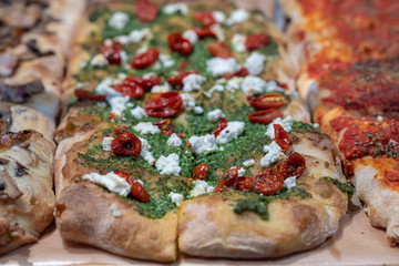 Crusty pizza slices with dried tomatos, pesto and fresh cheese