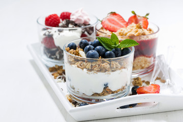 sweet desserts with fresh berries in glasses on white wooden tray