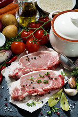 two pieces of raw pork and ingredients for soup, vertical