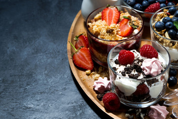 various desserts with berries and cream on dark background, top view