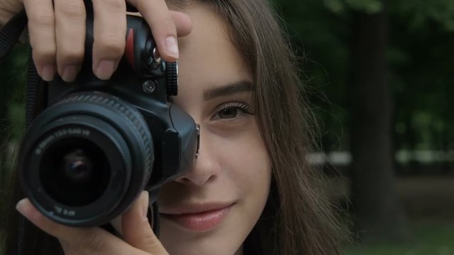 Charming girl takes pictures. Beautiful girl photographer close-up.