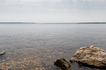 Big stones lie on sea beach. Coast. Nature background. Water with waves. Seascape