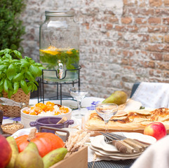 Family dinner in the courtyard of the house, autumn fruits and vegetables on the table, lemonade in a large bottle. Copy space, square,