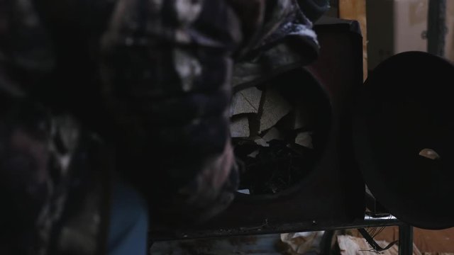 Cree man lighting woodstove inside camp tent, northern Quebec