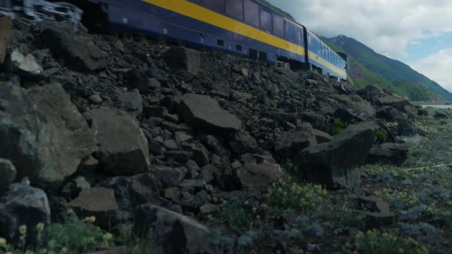 An Alaska railroad passenger train in Alaska travels along the ocean and mountains.