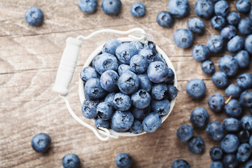 Blueberry or great bilberry in bucket on wooden table top view. Natural and organic superfood.