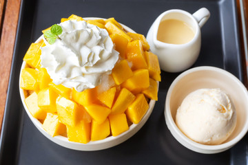 Shaved ice dessert served with mango sliced and whipping cream. Sweet dessert in Korean style. Local name, Bingsu.