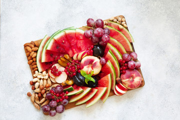 Obraz na płótnie Canvas Fruit salad with watermelon, plum, peach, red currant, grape on wooden tray over white background