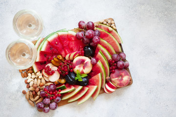 Fruit salad with watermelon, plum, peach, red currant, grape on wooden tray over white background