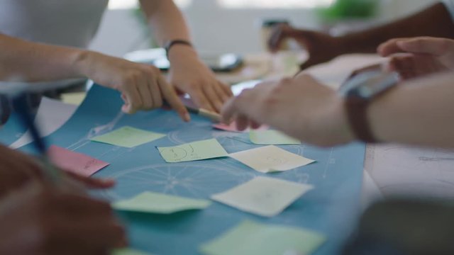 close up young diverse team group of people brainstorming ideas designing bicycle using blueprint discussing solutions in modern workspace