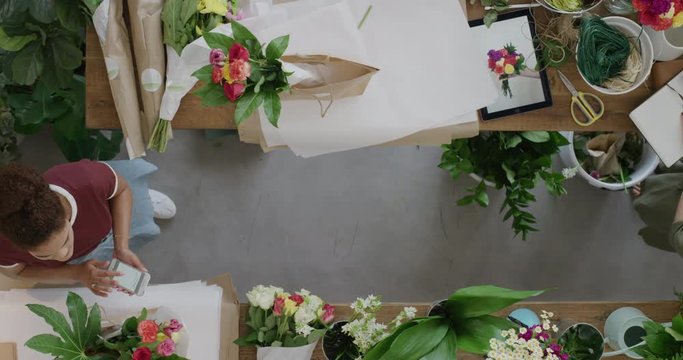 young florist business woman in startup flower shop checking stock preparing sales order working with female store manager top view 