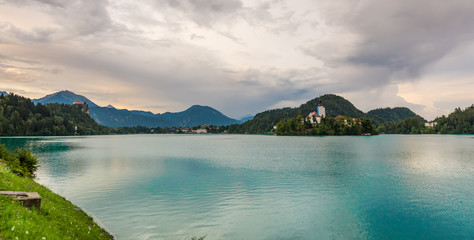 Bled lake with the island and church. Blue water and storm clouds.