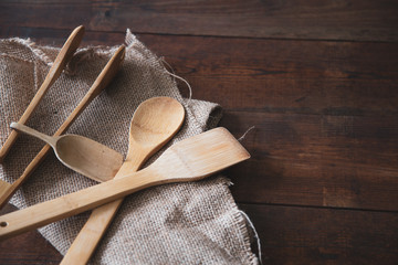Wooden kitchen utensils with sackcloth on wooden background
