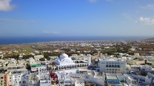 Part Two of Two of a continuous forward aerial shot over Thira, Santorini. A picturesque cliffside of restaurants and Villas stagger below, with a gorgeous blue Mediterranean Sea backdrop ahead.