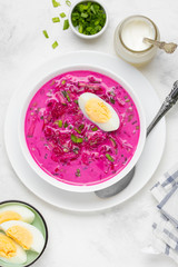 Cold borsch, summer beet soup with fresh cucumber, radish and boiled egg in white bowl. Traditional...