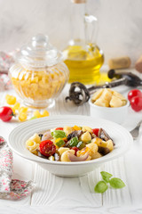 Italian pasta with fried vegetables and mushrooms, zucchini, cherry tomatoes, champignon, cheese and Basil. White plate