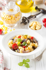 Italian pasta with fried vegetables and mushrooms, zucchini, cherry tomatoes, champignon, cheese and Basil. White plate