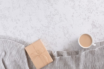 Cup of coffee with milk on white textured background with warm grey plaid, copy space. Flat lay,...