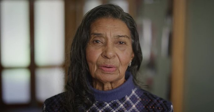 slow motion portrait of old indian woman relaxed breathing looking at camera in retirement home lobby