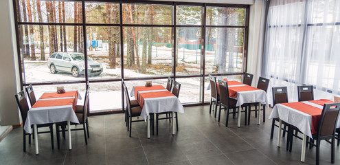 Dining tables and chairs in the restaurant. Big windows. Light interior