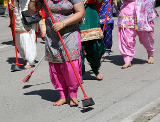 Sikh barefoot women  clean the street  during a religious celebr
