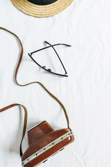 Vintage retro concept with photo camera, straw hat and glasses on white background. Flat lay, top view minimal photographer concept.