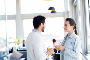 Obraz premium Happy young woman and her husband with glasses of juice cheering up during summer vacation in hotel cafe