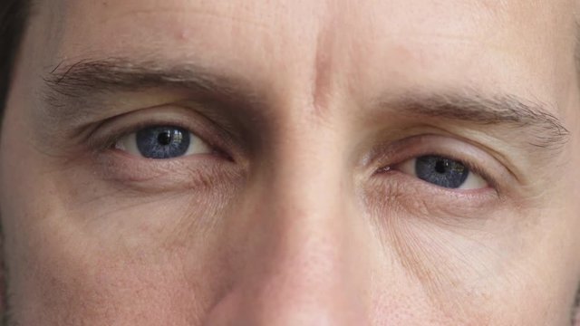close up of man beautiful blue eyes opening caucasian male awake looking at camera watching iris focus